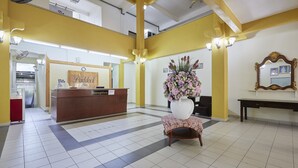 A reception area with a reception desk labeled "Paddock Inn Reception," a large floral arrangement, and a mirror on a wall. - Terengganu Equestrian Resort (Kuala Terengganu)