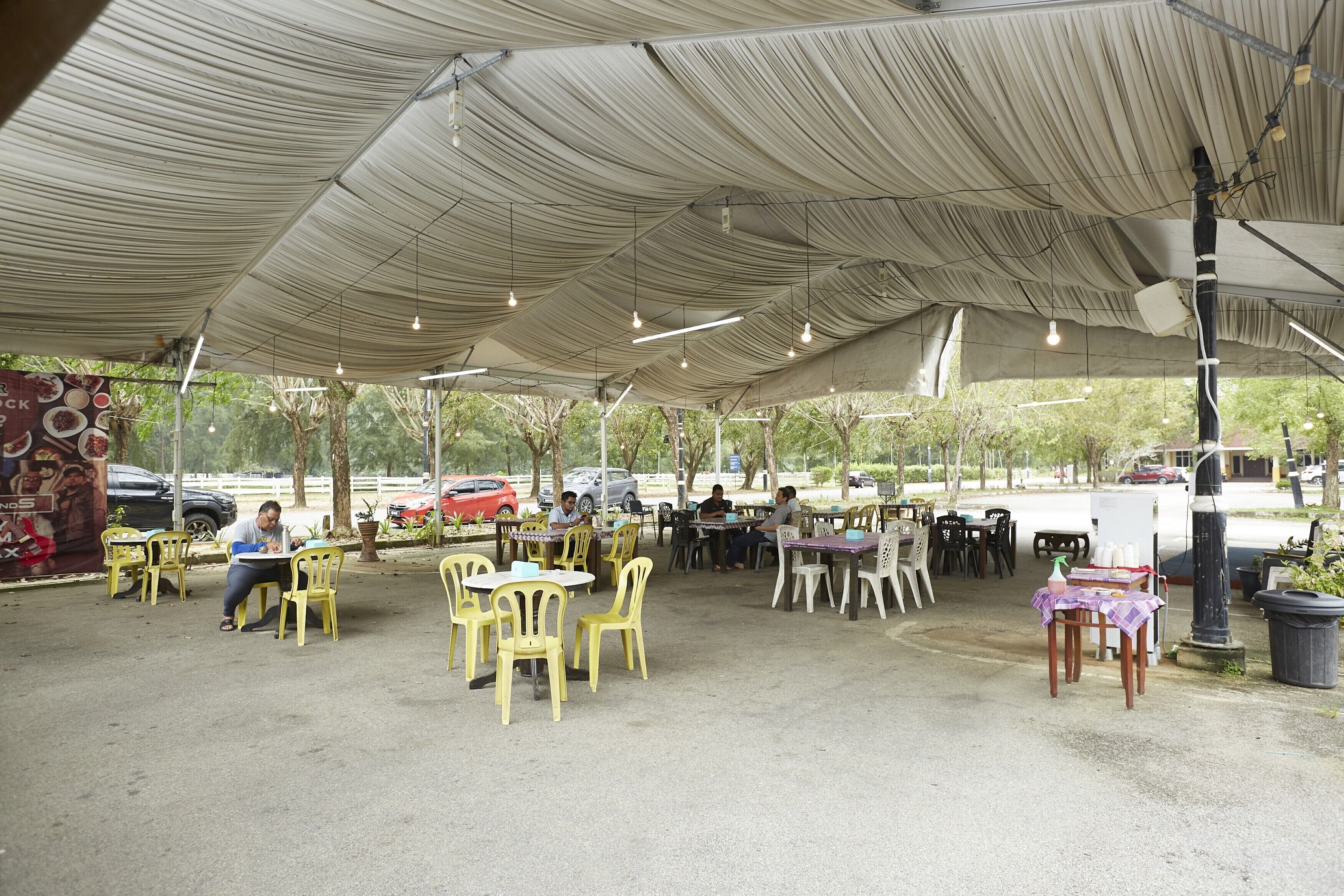 An outdoor seating area with tables and chairs under a large canopy.