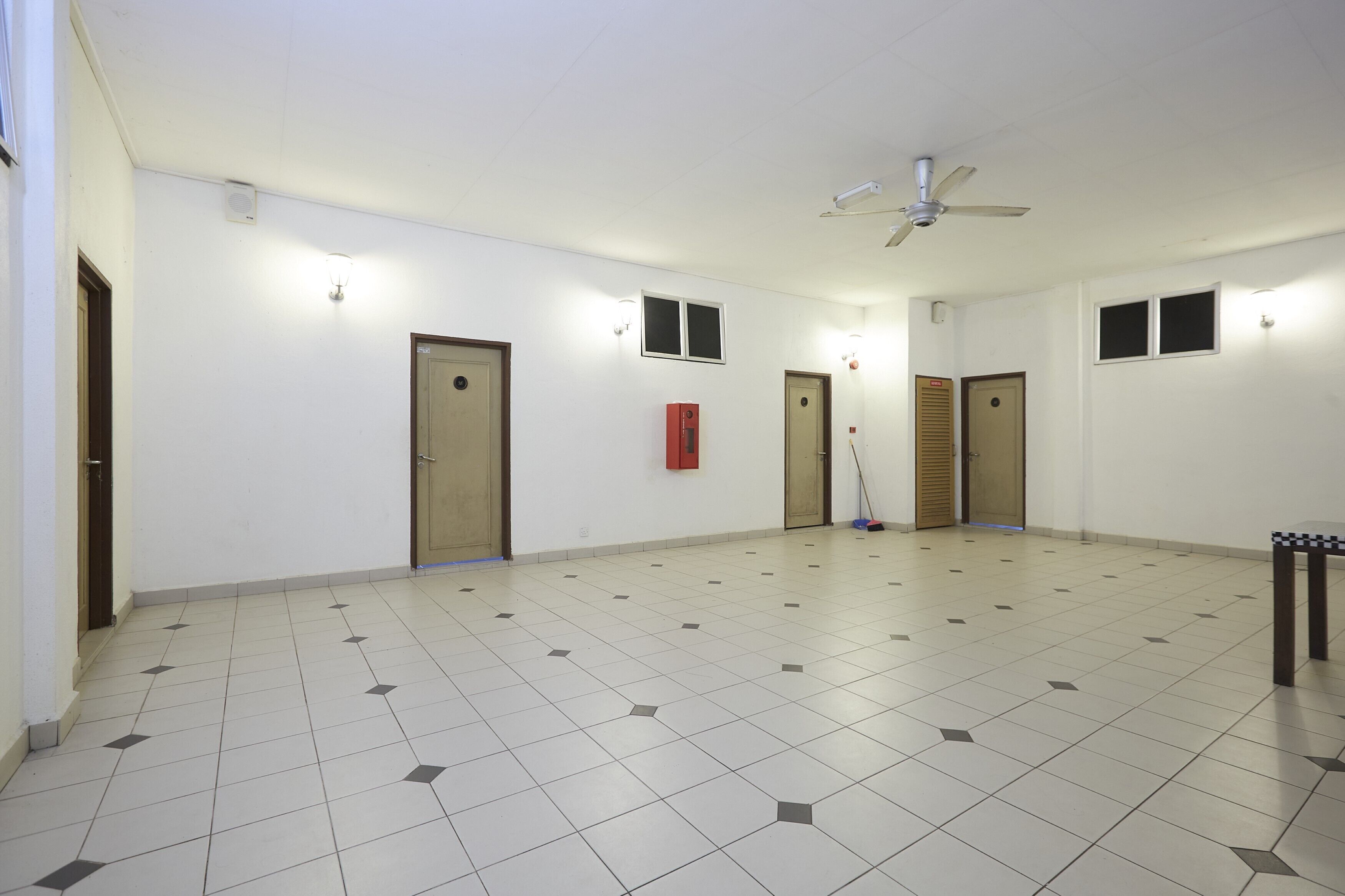 A spacious room with a tiled floor, a ceiling fan, and multiple doors.