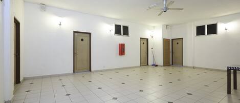 A spacious room with a tiled floor, a ceiling fan, and multiple doors.