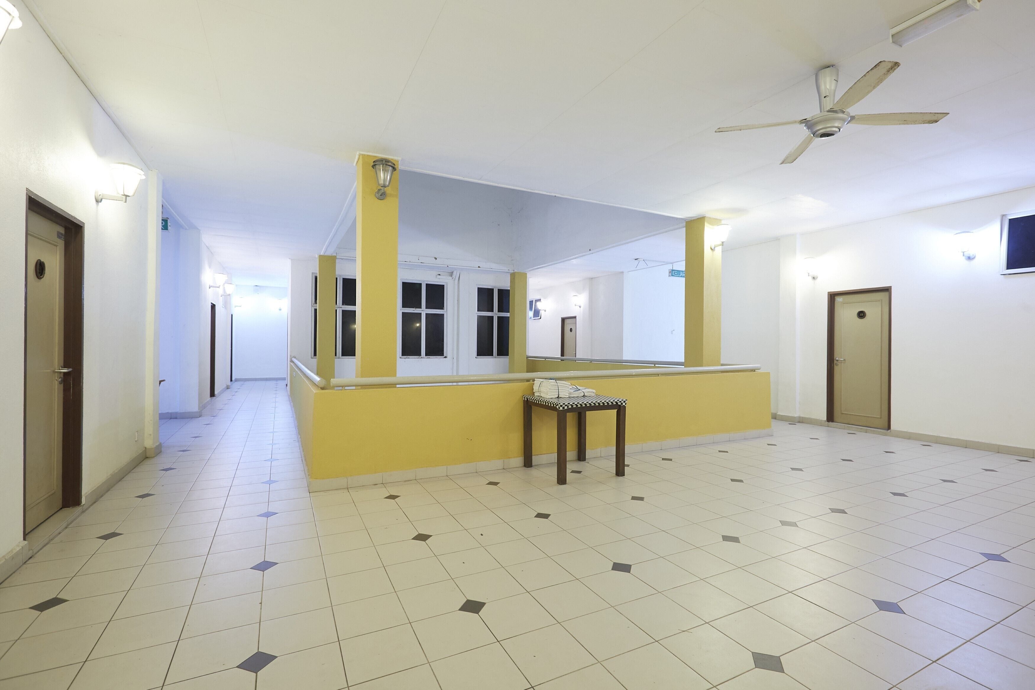 A hallway with a yellow accent wall, a ceiling fan, and a tiled floor.