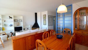 Un comedor con mesa de madera, sillas, un televisor y un aparador de marco azul.