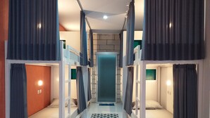Um corredor com beliches, um chão estampado e uma porta no final.