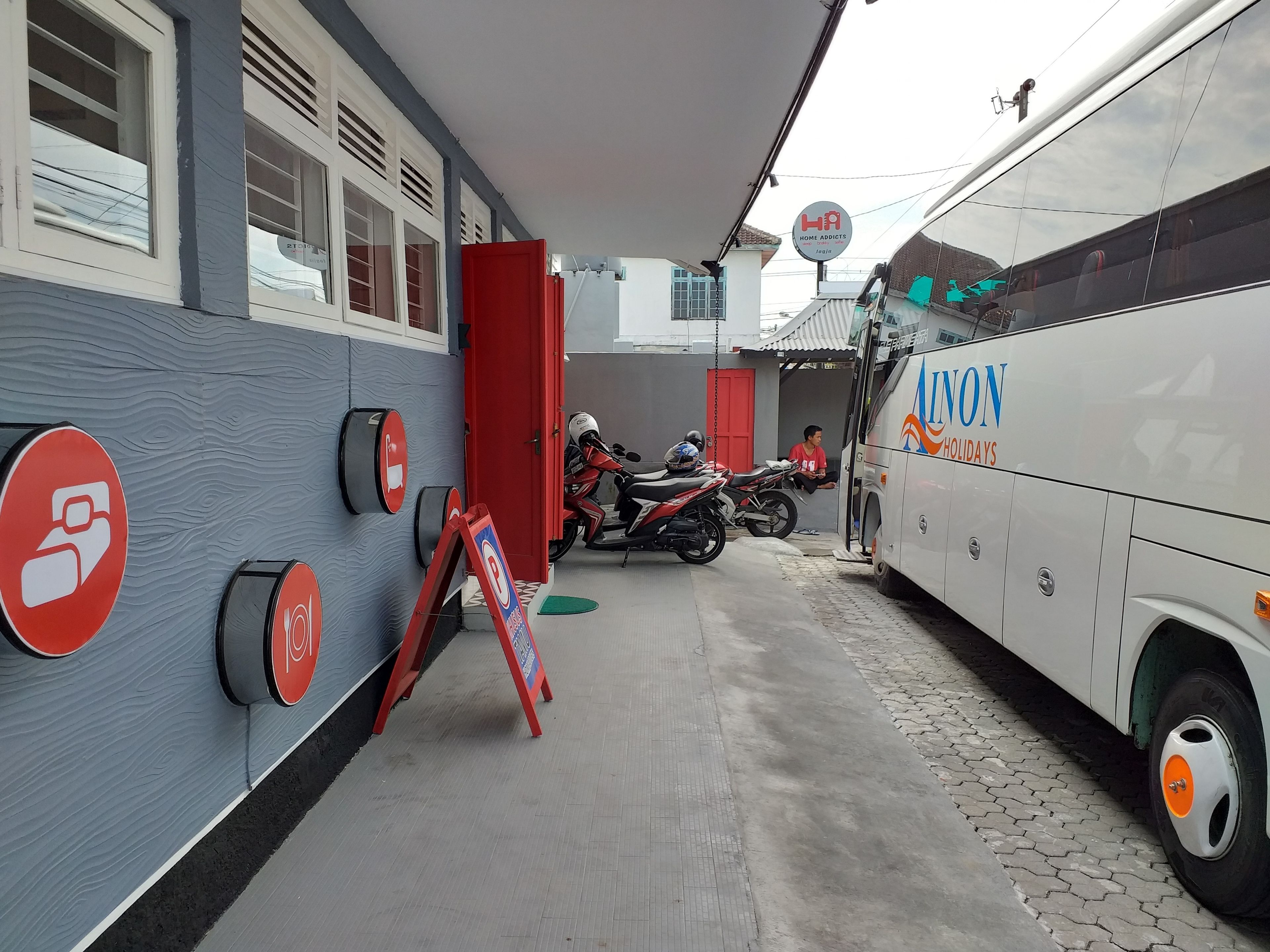 A building with a grey facade, a red door, and a sign indicating a no parking zone.