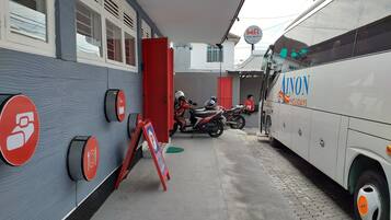 A building with a grey facade, a red door, and a sign indicating a no parking zone.