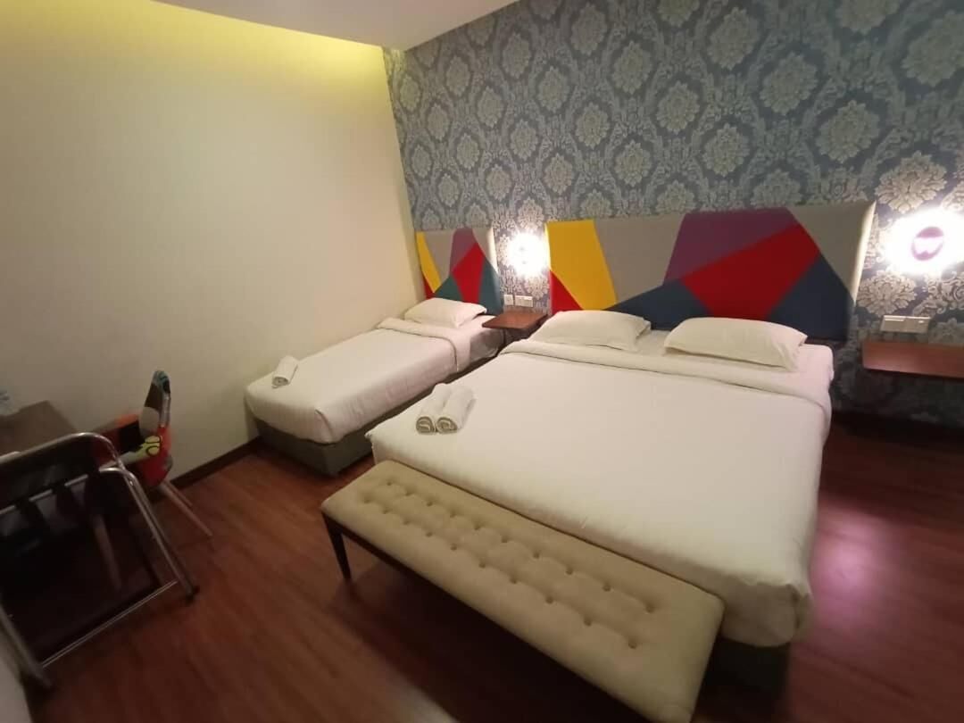 Una habitación de hotel con dos camas, un banco y una mesita.