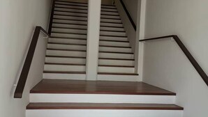 A staircase with wooden steps and white walls, leading to an upper floor.