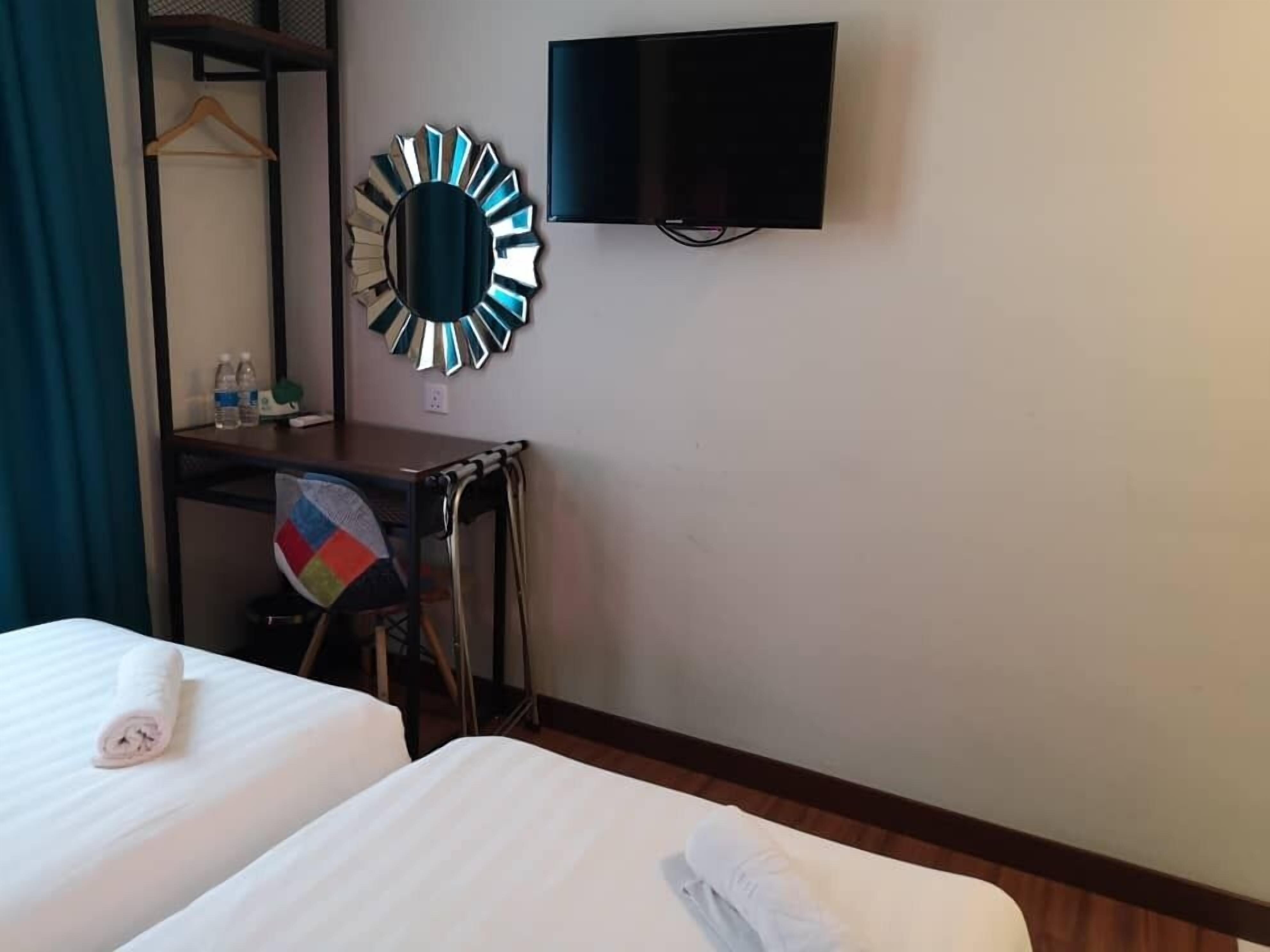 Une chambre d’hôtel avec deux lits, un bureau avec une chaise, une télévision et un miroir.