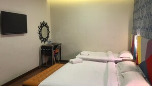 A hotel room with two beds, a bench, a TV, and a mirror.