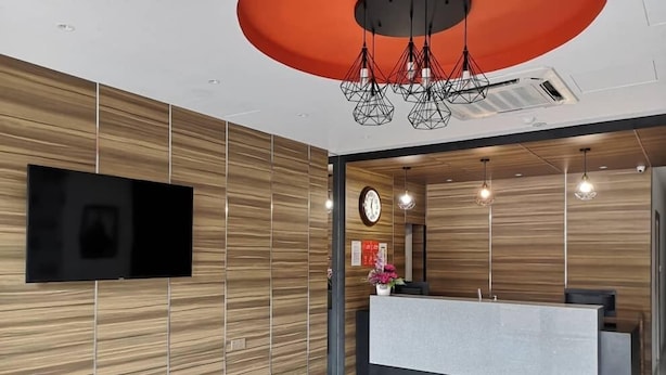 A modern reception area with a wooden wall, a flat-screen TV, a reception desk, and a clock.