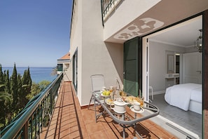 Enjoy a meal on the balcony with a view of the sea, surrounded by a dining table and comfortable seating.