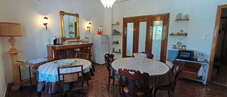 A dining area with a chandelier, a refrigerator, a microwave, and a dining table with chairs.