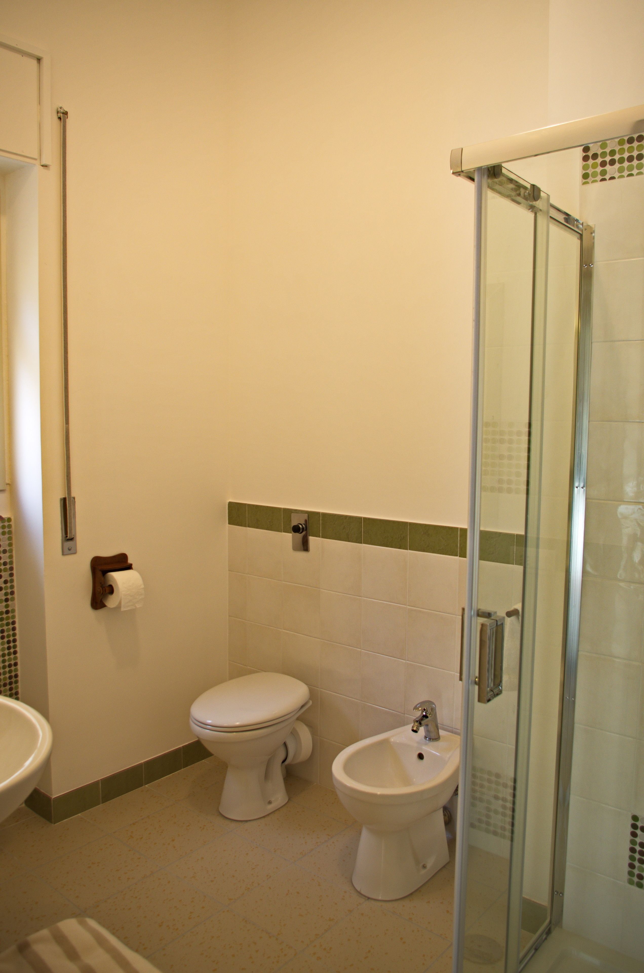 Une salle de bain comprenant des toilettes, un bidet et une cabine de douche en verre.