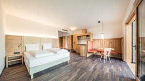 Een moderne slaapkamer met een groot bed, een klein bureau en een zithoek met een fauteuil.