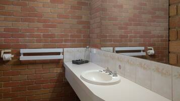 A bathroom with a white sink, a mirror, and a brick wall.