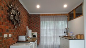 Uma cozinha compacta com parede de tijolos, geladeira branca, pia e bancada de madeira.