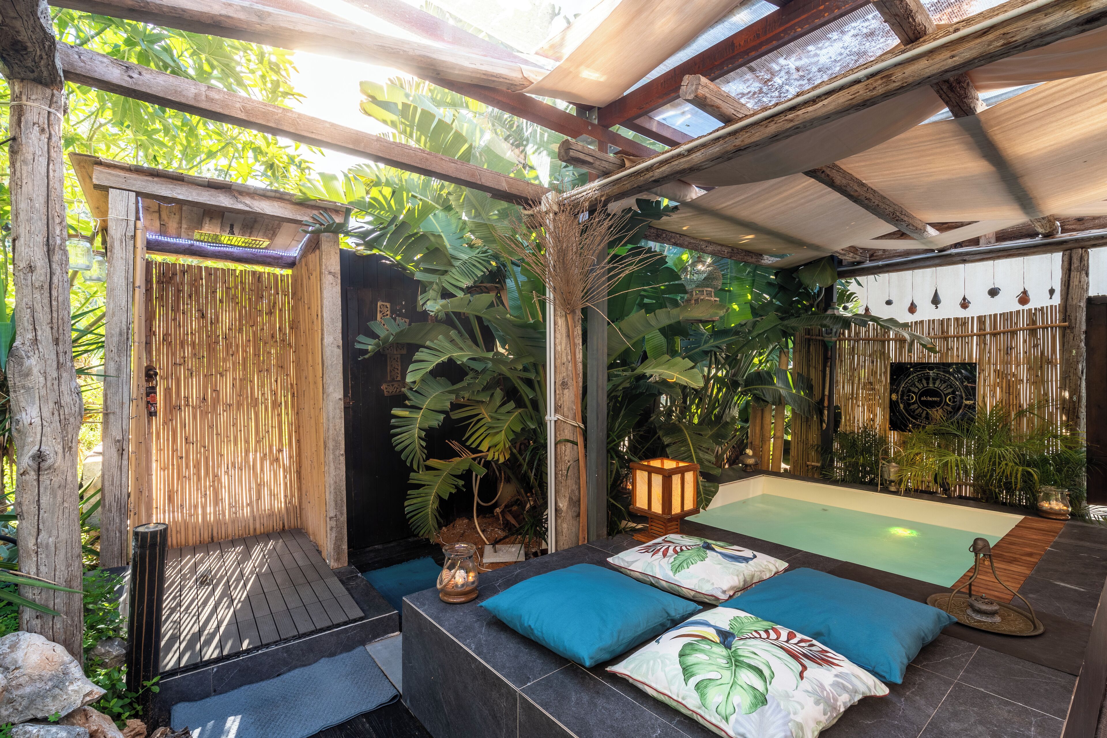 A spa area with a wooden deck, a hot tub, and a bamboo wall.