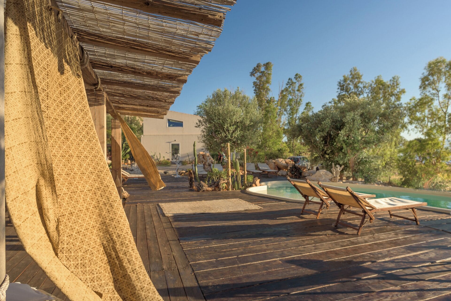 A wooden deck with lounge chairs and a pool.