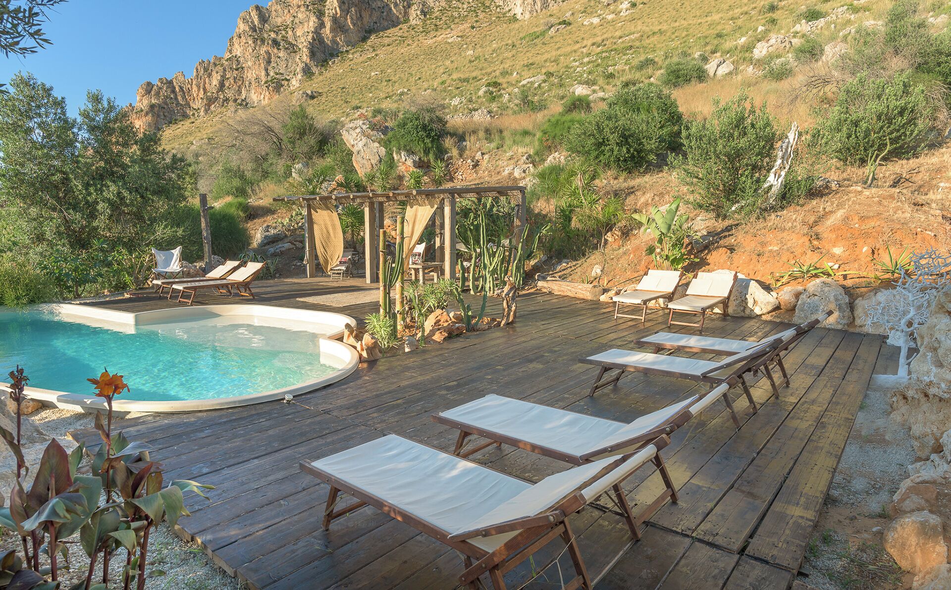 Un área de piscina con sillones de descanso y una pérgola.