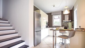 A modern kitchen with a stainless steel refrigerator, a bar area with stools, and a staircase leading to another level. - 3 bedroom lovely home in Cisano sul Neva (Cisano sul Neva)