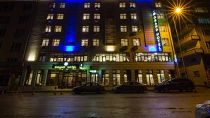 A hotel with a prominent "Grand Hotel" sign, multiple floors, and a brightly lit facade. - An Grand Hotel (Ankara)