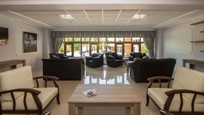 A spacious living room with leather sofas, a wooden coffee table, and large windows offering a view of the outside. - An Grand Hotel (Ankara)