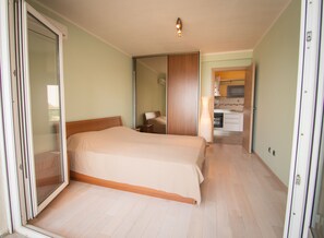 Une chambre avec un lit, une porte coulissante et une vue sur un espace cuisine.