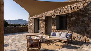 A stone building with a patio area featuring a wicker chair, a sofa, and a table.