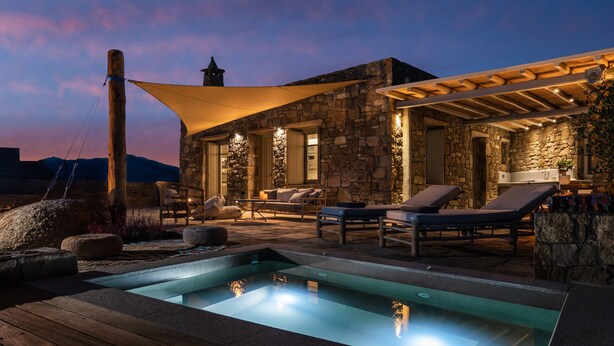 Ein Gebäude aus Stein mit Pool, Liegestühlen und einer überdachten Terrasse.