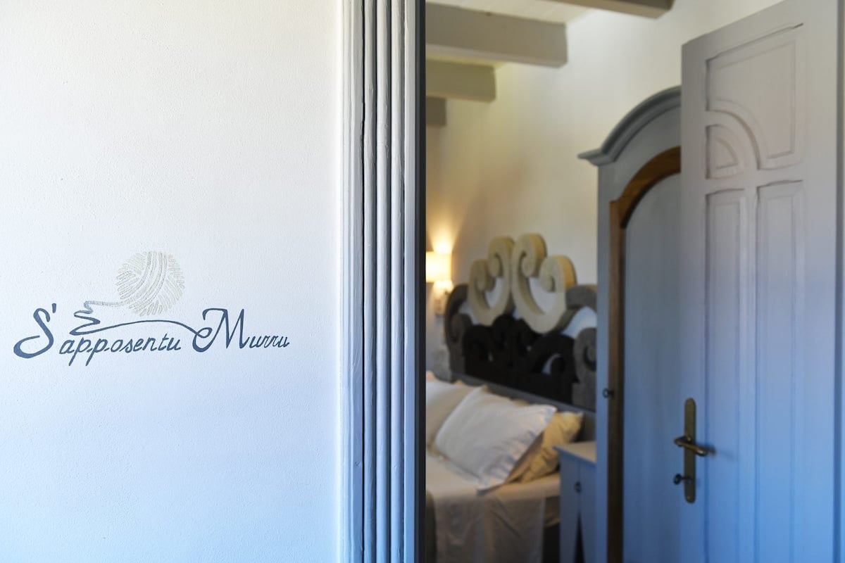 Ein Hotelzimmer-Eingangsbereich mit Bett, Nachttisch und einer Wand mit einem Logo.