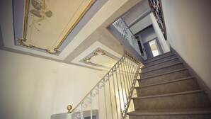 A grand staircase with ornate metal railings and a decorative ceiling. - Bisos Ospitalità diffusa eco-sostenibile (Paulilatino)