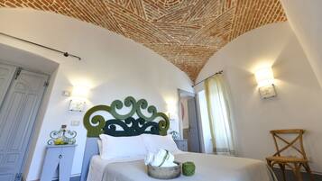 A bedroom with a brick-patterned ceiling, a bed with white linens, a wooden chair, and a nightstand with a lamp.