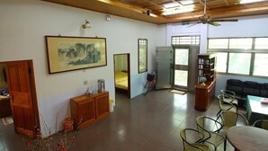 A spacious room with a high ceiling, wooden beams, a dining area with chairs and a table, a refrigerator, a bicycle, and a large framed artwork on the wall. - Duan Yuan Homestay (Lukang)