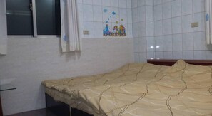 A room with a bed, a window with curtains, and a wall with a children's drawing.