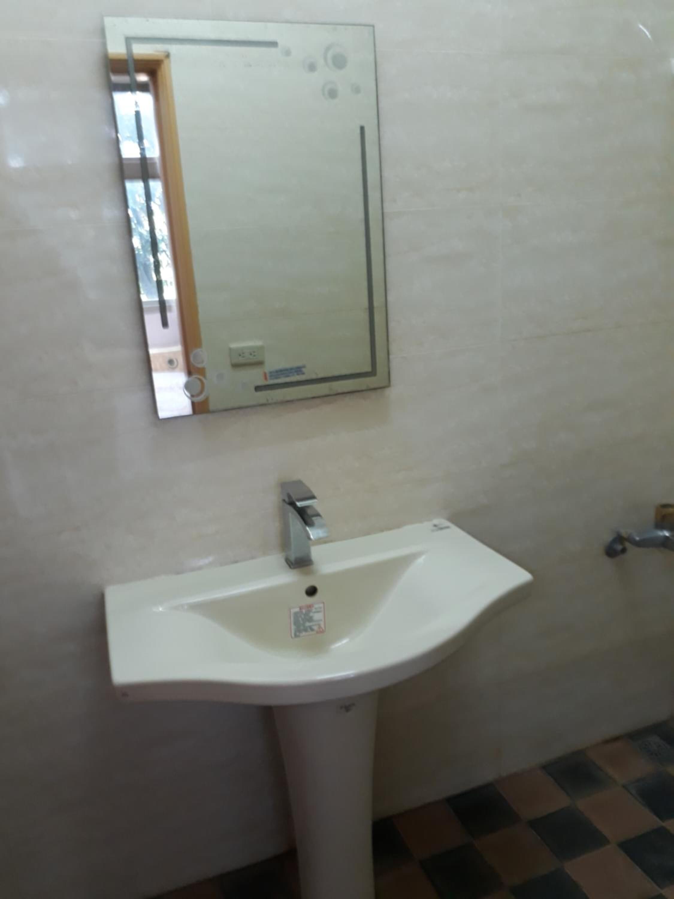 Un bany amb un lavabo blanc, un mirall i un sòl de rajola.