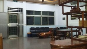 A living room with a sofa, a dining table with chairs, a wooden cabinet, and a window with blinds. - Duan Yuan Homestay (Lukang)
