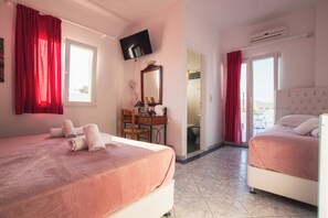 Camera d'albergo con due letti, una scrivania, una sedia, una televisione e bagno visibile attraverso una porta aperta.