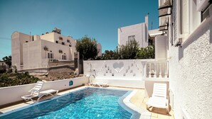 En swimmingpool med hvide liggestole og et hjerteformet design på væggen.
