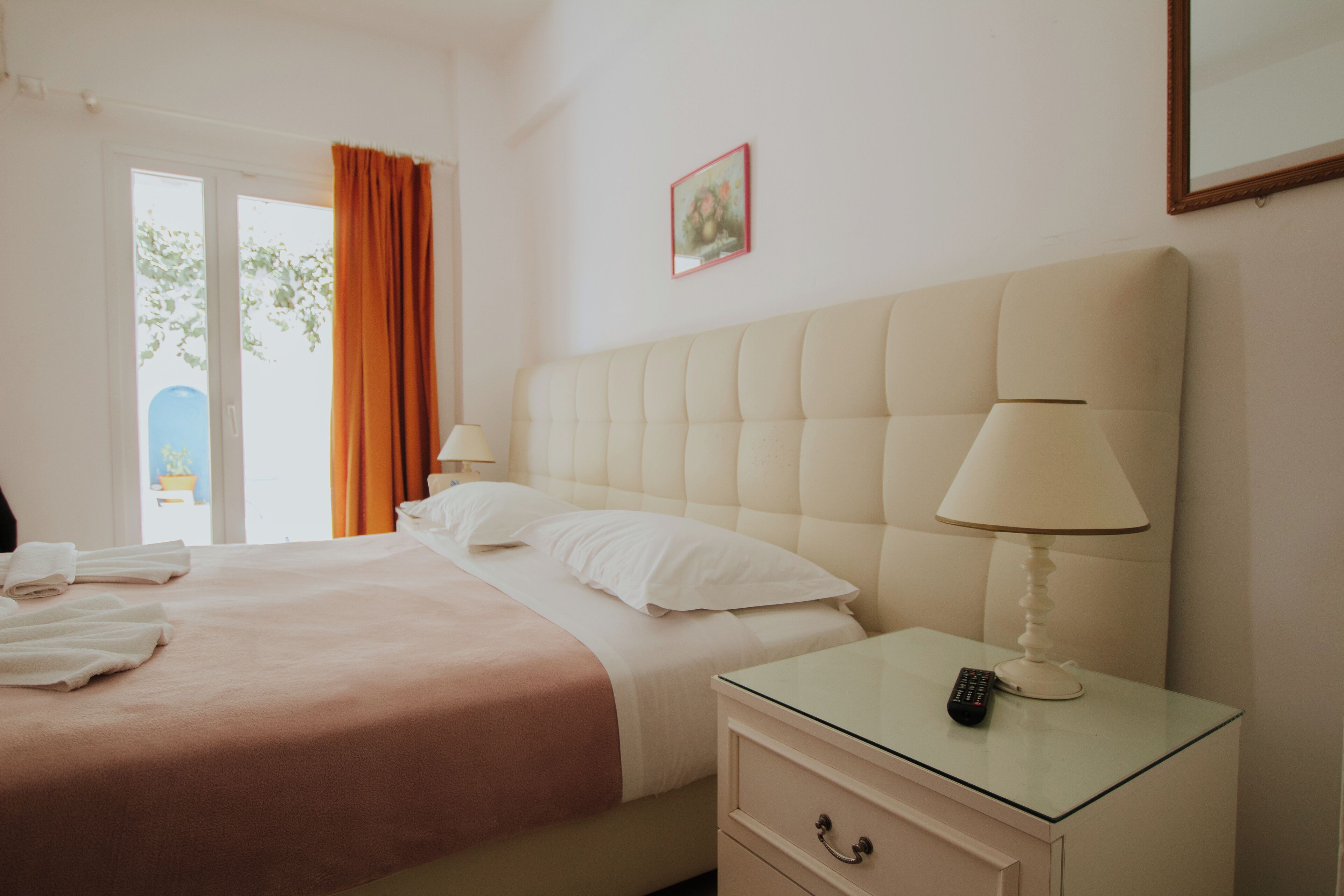 Una habitación de hotel con cama, mesita de noche y ventana con cortinas.