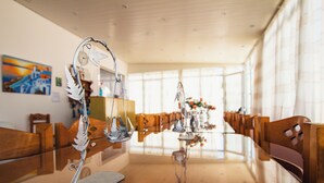 Et spiseområde med et langt træbord, stole og en dekorativ metalkunst.
