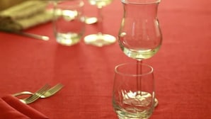 Une table à manger dressée avec des couverts et des verres, recouverte d’une nappe rouge.
