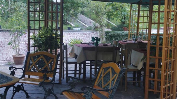 Une terrasse extérieure avec des meubles en bois, un sol en pierre et des plantes en pot.