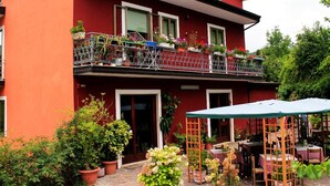 Un bâtiment rouge doté d’un balcon et d’un espace extérieur aménagé pour s’asseoir.
