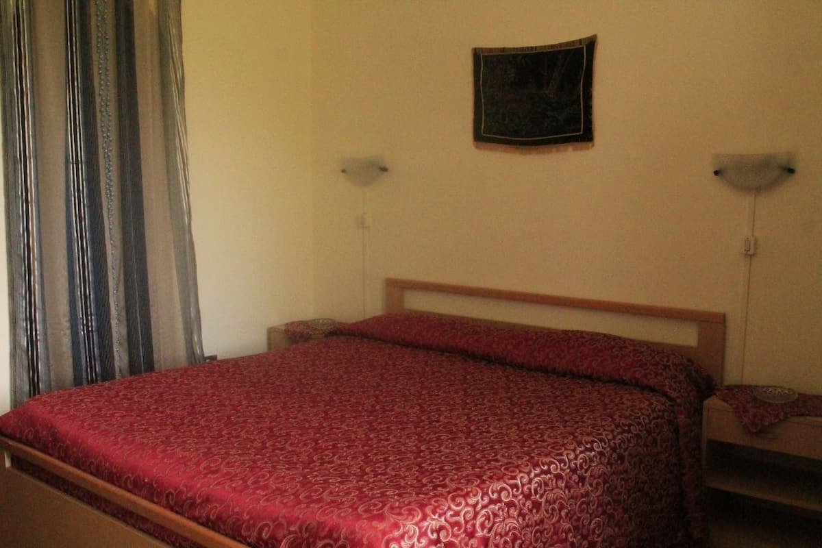 Una cama individual con cabecera de madera en una habitación con pared lisa y un pequeño marco de fotos.