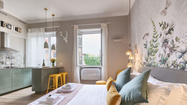 Una moderna camera d'hotel con un letto grande, un angolo cottura e un balcone con vista.