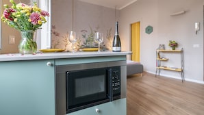 Una cucina moderna con forno a microonde integrato, un vaso di fiori e calici da vino sul piano di lavoro.