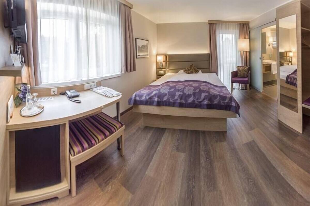 Ein Hotelzimmer mit Bett, Schreibtisch, Stuhl und begehbarem Kleiderschrank.