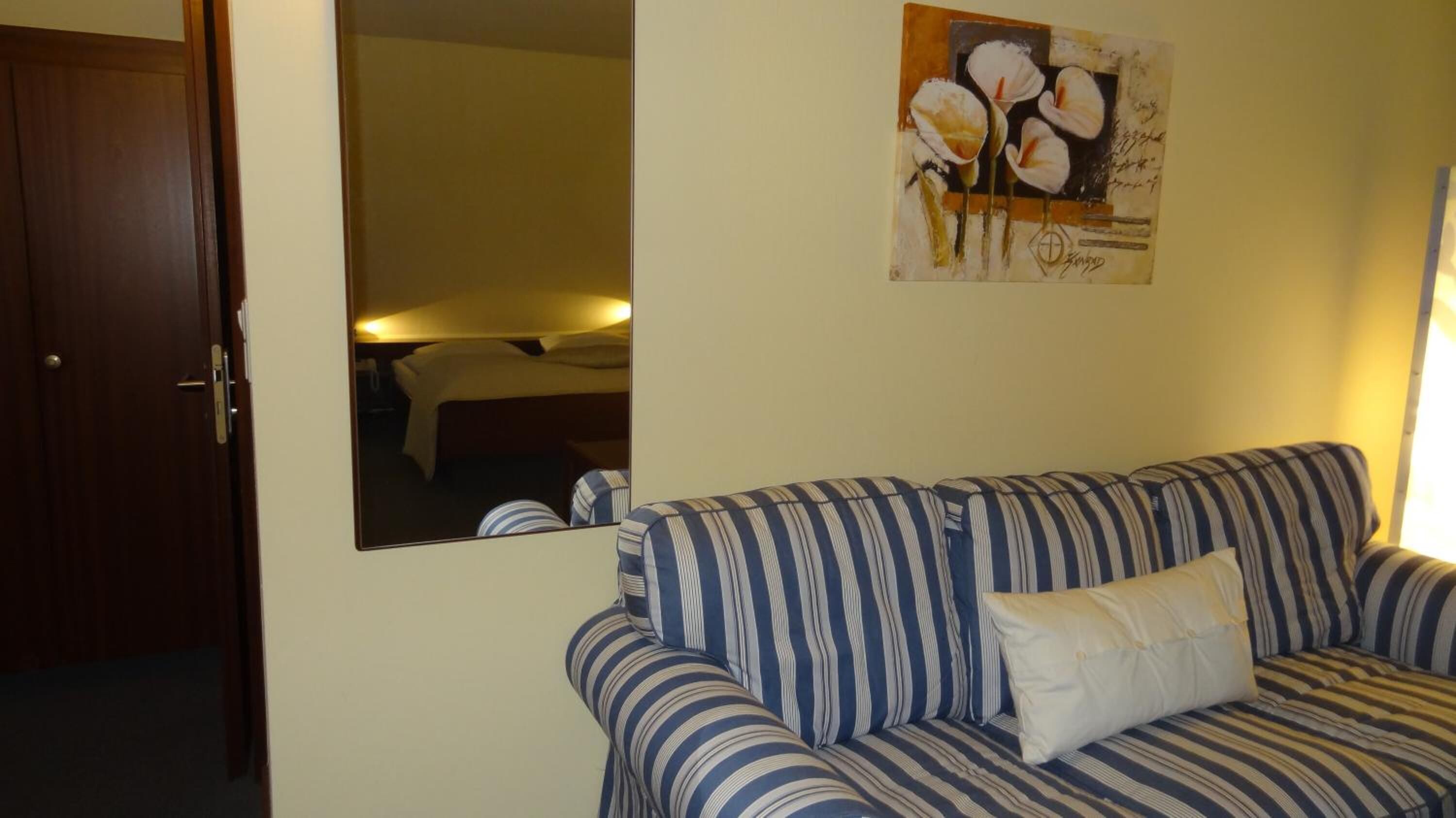 Una habitación con sofá a rayas, una cama y un cuadro en la pared.