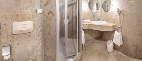 A bathroom with a glass shower enclosure, a sink with a mirror, and a towel rack.