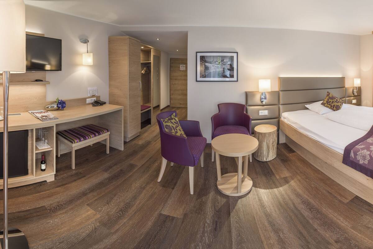 Ein Hotelzimmer mit Bett, Schreibtisch, Stuhl und einem kleinen Tisch.